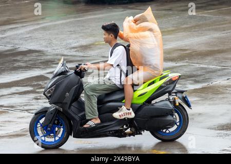 SAMUT PRAKAN, THAILAND, 20. März 2024, Pärchen fahren auf einem Motorrad bei Regen Stockfoto