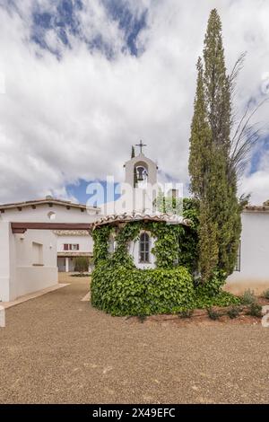 Hauptfassade eines Landhauses im andalusischen Stil mit einer kleinen privaten Eremitage bedeckt mit Vegetation mit weißen Wänden, Schotterweg, ein neu bepflanztes Or Stockfoto