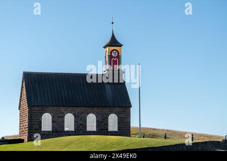 Eine kleine Kirche mit rotem Dach und einer Uhr vorne. Die Uhr ist auf 10:00 Uhr eingestellt Stockfoto
