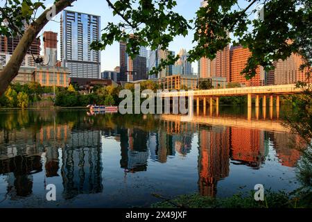 Lady Bird Lake spiegelt die Skyline der modernen Stadt Austin Texas wider. In der blauen Stunde fährt ein kleines Boot entlang der Küste. Stockfoto