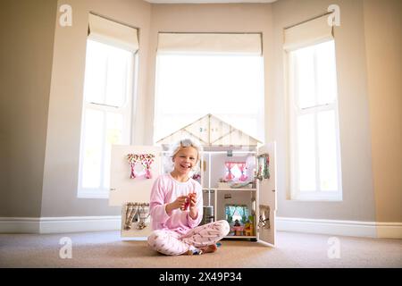 Puppenhaus, Porträt und Mädchen zu Hause spielen mit Spielzeug für Wachstum, Entwicklung und Spaß. Lächeln, süßes und junges Kind mit 3D-Apartment-Figur Stockfoto