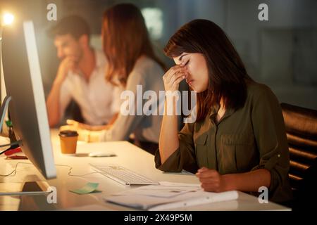 Frau, Texter und Kopfschmerzen bei der späten Arbeit, Burnout und müde im Büro mit Kollegen, Desktop und Notebook. Weibliche Person, kreativ und müde Stockfoto