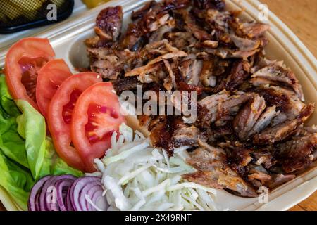 Gyros: Saftige, gewürzte Fleischscheiben, perfekt gegrillt, in eine warme Pita gewickelt, mit frischen Tomaten, Zwiebeln und cremiger Tzatziki-Sauce garniert Stockfoto