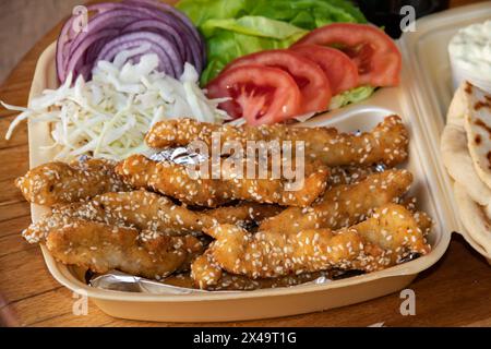 Sesam-beschichtete gebratene Streifen, serviert mit frischem Salat auf einem Essenstablett. Stockfoto