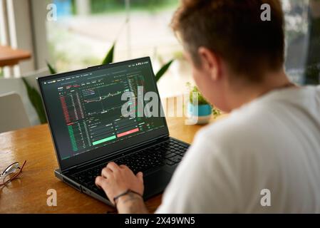 Fokussierter Krypto-Trader analysiert Markttrends auf Notebooks im Coworking Space, Blockchain-Analysen sind auf dem Bildschirm sichtbar. Person handelt mit digitaler Währung Stockfoto