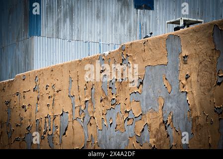 Bräunliche Farbe, gerissene und abblätternde Farbe auf der Betonwand von den Elementen, was zum Zerfall der Struktur führt und gleichzeitig eine intellektuelle Textur und Patina freigibt Stockfoto