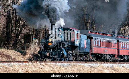 Ronks, Pennsylvania, USA, 17. Februar 2024 - Eine Dampfeisenbahn fährt die Gleise entlang und hinterlässt eine Rauchspur. Der Zug ist umringt Stockfoto