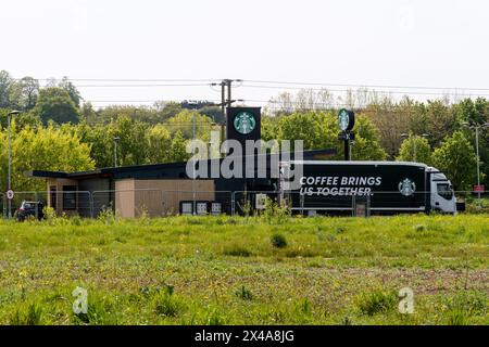 Starbucks Drive-Thru Coffee Shop mit Lieferwagen oder LKW mit Kaffee bringt uns zusammen auf Side, Tongham Services, Surrey, England, Großbritannien Stockfoto