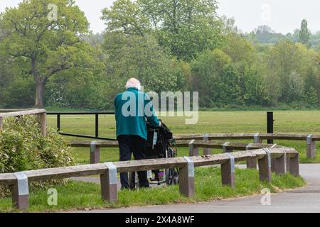Älterer Mann, der seine behinderte Frau im Rollstuhl betreut, England, Großbritannien. Konzept: Unbezahlte Betreuungspersonen, unzureichende Betreuung von Alten und Behinderten Stockfoto