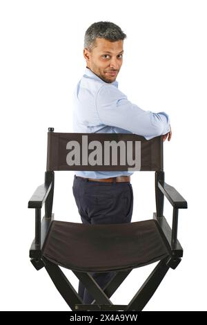 Ein Mann steht vor einem Stuhl mit überkreuzten Armen Stockfoto