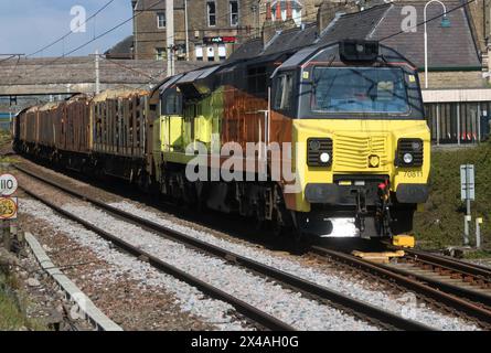 Colas Rail Freight Class 70 Diesel-elektrische Lok 70811, die Holzfrachtzug durch Carnforth auf der West Coast Main Line am 1. Mai 2024 transportiert. Stockfoto