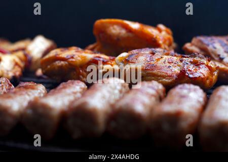 BBQ, Grill für Picknick mit Schweinefleisch, Rindfleisch, Hühnerfleisch und Flügeln mit Fleischbällchen auf offenem Feuer mit Orangenflammen und Rauchgrill mit Nahaufnahme Stockfoto