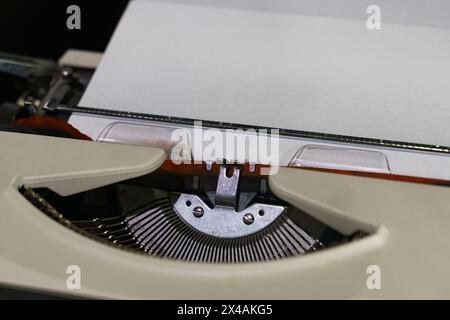 Eine detaillierte Ansicht einer altmodischen Schreibmaschine mit eingelegtem Blatt Papier, die Vintage-Design und Funktionalität zeigt. Stockfoto