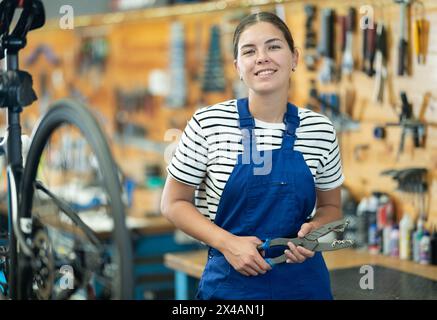 Junge Arbeiterin posiert mit Fahrradwerkzeug Stockfoto