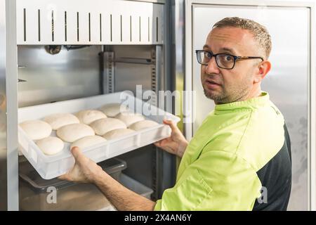 Pizzateigbällchen in den Kühlschrank stellen, professioneller Koch. Hochwertige Fotos Stockfoto