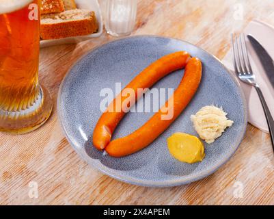 Dünne Frankfurter serviert mit weißem Meerrettich, Senf und Bier Stockfoto