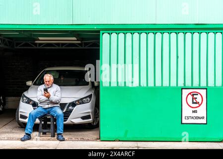 Ein Mann sitzt vor Einer Garage in Valparaiso, Region Valparaiso, Chile. Stockfoto