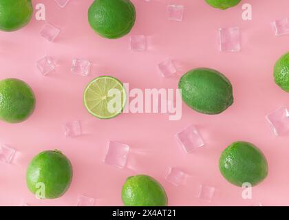 Kreatives Sommermuster aus grüner Limette und Eiswürfeln auf hellem pastellrosa Hintergrund. Fruit Minimal Konzept. Trendiges gesundes Lebensmittelmuster. Stockfoto