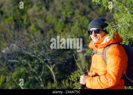Porträt eines jungen lächelnden Mannes, aufgenommen in einem Wald vor grünem Hintergrund. Wanderungen auf dem Berg Vrmac, Montenegro. Stockfoto