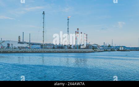 Balikpapan, Indonesien - 14. April 2024. Eine große Pertamina-Ölraffinerie mit Lagertanks, Rohren und Schornsteinen befindet sich am Ufer eines blauen Ozeans. Stockfoto