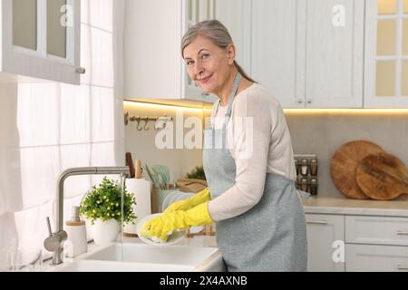 Glückliche Hausfrau Waschplatte in Küchenspüle Stockfoto