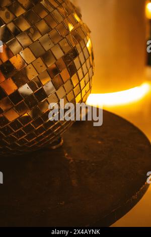 Discokugel in Vintage-Silber mit Spiegeln auf einem runden Tisch auf dunklem Hintergrund. Vertikale Fotoparty. Details zur Einrichtung im Nachtklub. Entspannungskonzept Stockfoto