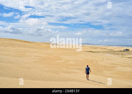 Mann, der durch weite Sanddünen läuft Stockfoto