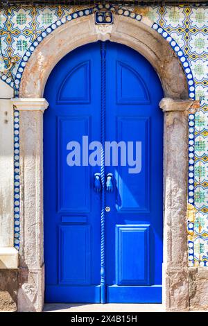 Eine blaue Tür, an der ein Seil hängt, Tavira, Algarve, Portugal. Stockfoto