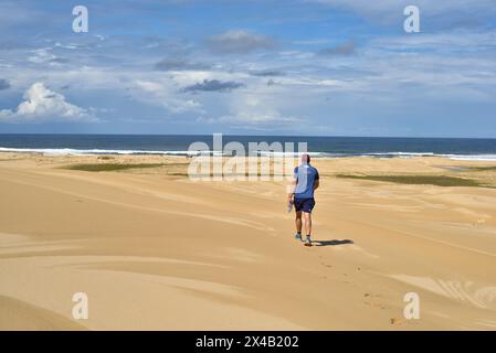 Mann, der durch weite Sanddünen läuft Stockfoto