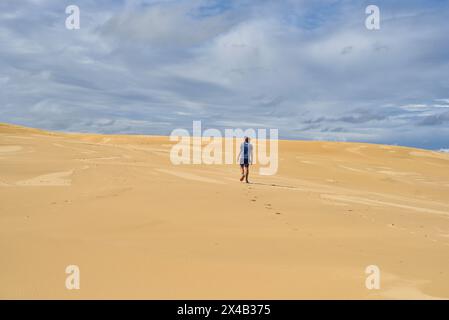 Mann, der durch weite Sanddünen läuft Stockfoto