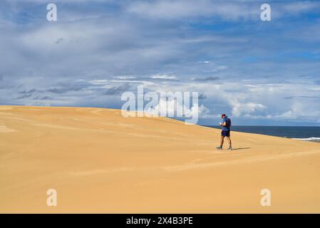 Mann, der durch weite Sanddünen läuft Stockfoto