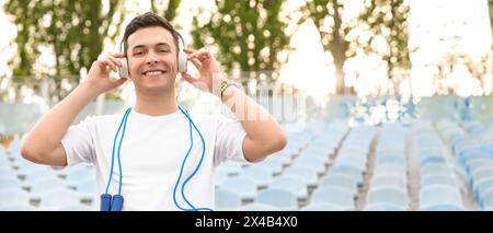 Sportlicher junger Mann mit Seilspringen und Musik im Stadion hören Stockfoto