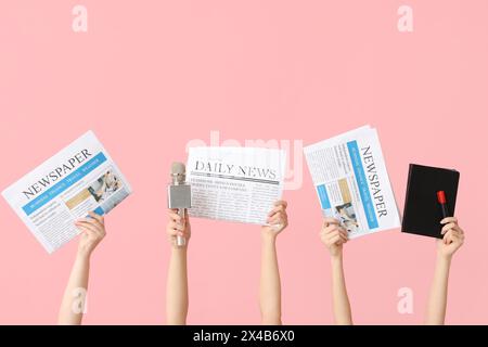 Weibliche Hände mit Zeitungen, Notizbuch und Mikrofon auf rosa Hintergrund Stockfoto