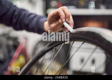 Nicht erkennbare Person, die an einem Fahrradgemälde arbeitet. Zeit zum Entfernen des Abdeckbands der Radfelge. Nahansicht. Stockfoto