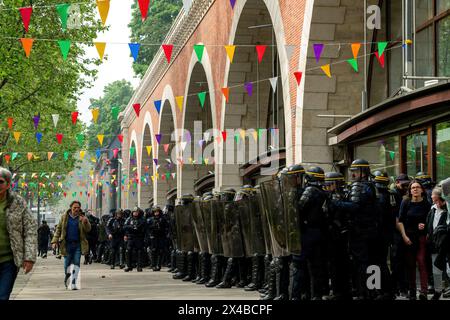 Aufruhr-Polizei aus einer Schlange, um das Fenster einer Kunstgalerie während des jährlichen marsches zum Internationalen Arbeitertag in Paris am 1. Mai, Mai, zu schützen. Während der Proteste im Mai lauern die Pariser Straßen mit Feuerwerken und Stuntgranaten, während die Arbeiter ihre Rechte in einem Meer von Spruchbändern und Gesängen behaupten. Inmitten der Inbrunst brechen Zusammenstöße zwischen Demonstranten und Aufstandspolizisten aus, Tränengas füllt die Luft, während die Spannungen eskalieren. Die Veranstaltung unterstreicht den anhaltenden Kampf für Arbeitnehmerrechte und soziale Gerechtigkeit, während Aktivisten sich in einem kollektiven Aufruf zum Wandel auf den Straßen der französischen Hauptstadt vereinen. Stockfoto