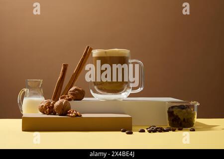 Der Hintergrund der Getränkewerbung hilft, den Geist wach zu halten. Tasse Kaffee mit Bohnen, Zimtstangen, Walnuss und Milch auf braunem Hintergrund. Stockfoto