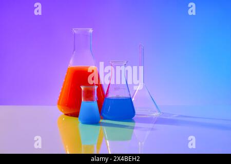 Nahansicht der mit Laborglas gefüllten Farblösung auf blauem und violettem Hintergrund mit Farbverlauf. Konzept: Forschung, Biochemie, Natur, Pharmazie Stockfoto