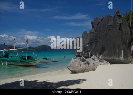 Ein beliebter Ort, an dem Touristen Halt machen, um zu Mittag zu essen und sich mit dem klaren blauen Wasser und dem weichen Wasser zu entspannen. Weißer Sandstrand bei Banul Island in der Nähe von Coron Stockfoto