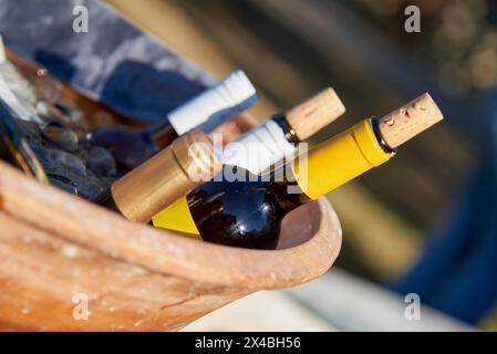 Gekühlte Flaschen Wein in einem Terrakotta-Behälter mit Eis, ideal für Speisen im Freien Stockfoto