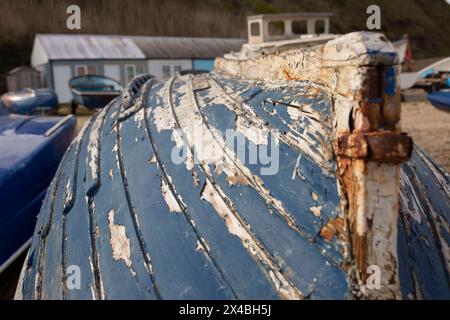 Altes beschädigtes Holzruderboot mit abblätternder Farbe, das auf dem Anleger eines Fischerhafens verlassen wurde. Stockfoto