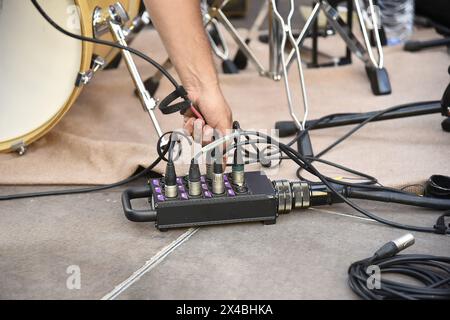 Handanschluss von Kabeln an eine Anschlussdose auf einer Bühne, Vorbereitung auf ein Konzert im Freien Stockfoto