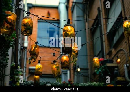 Umfunktionierte maurergläser beleuchten eine urbane Gasse. Stockfoto