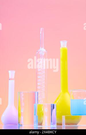 Verschiedene Laborgeräte auf rosafarbenem Hintergrund. Laborglas mit Farbflüssigkeit, dekoriert mit Zylinderglaspodien für di Stockfoto