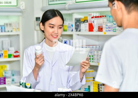 Weibliche Apothekerin in der Hand eines Medikamentenboxen, die Kunden im Apothekengeschäft beraten Stockfoto