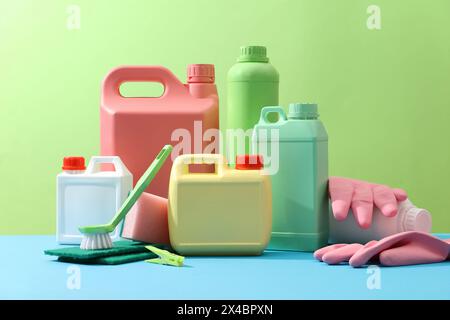 Reinigungsprodukte auf grünem Hintergrund mit leeren Flaschen für Reinigungsmittel, Gummihandschuhe, Bürsten und Schwämme. Kreative Ideen für Stockfoto