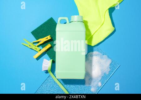 Wäschespinder, eine Plastikflasche, eine Toilettenbürste, ein Schwamm, ein Baumwollhandtuch und eine Glasplatte auf blauem Hintergrund. Das Konzept von Badezimmerhygieneprodukten. Anzeige Stockfoto