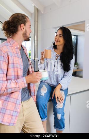 Diverse Paare genießen Kaffee in der Küche zu Hause. Sie hat langes schwarzes Haar, hellbraunes Haar und Bart, unverändert Stockfoto