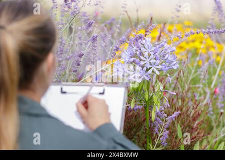 Die Frau macht Notizen in einem Blumengewächshaus Stockfoto