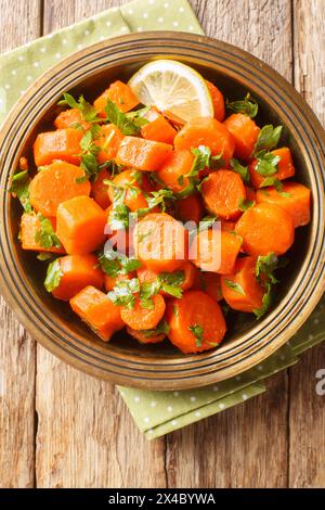 Marokkanischer Möhrensalat mit würziger Zitrone, warmen Gewürzen und frischen Kräutern gemischt mit Olivenöl, Knoblauch und Kümmel auf dem Teller auf dem Tisch. Vertica Stockfoto