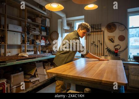 Tischlerei Werkstatt, Profi-Handwerker arbeiten. Man Schreinermeister Handwerker arbeitet mit der Oberfläche des Tisches Stockfoto